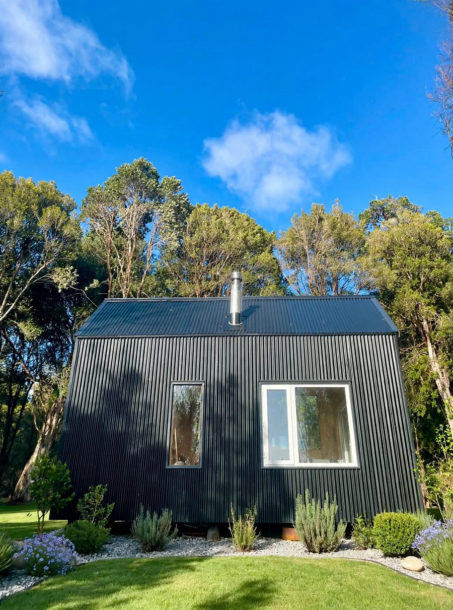 Tiny house de Modus Patagonia, revestimiento negro acanalado, rodeada de bosque nativo
