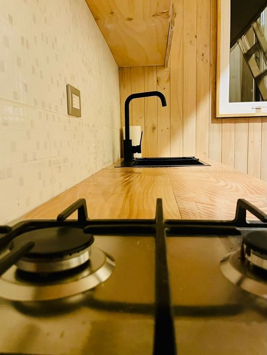 Cocina Tiny Belbén: grifería negra, mesón de madera y cocina a gas